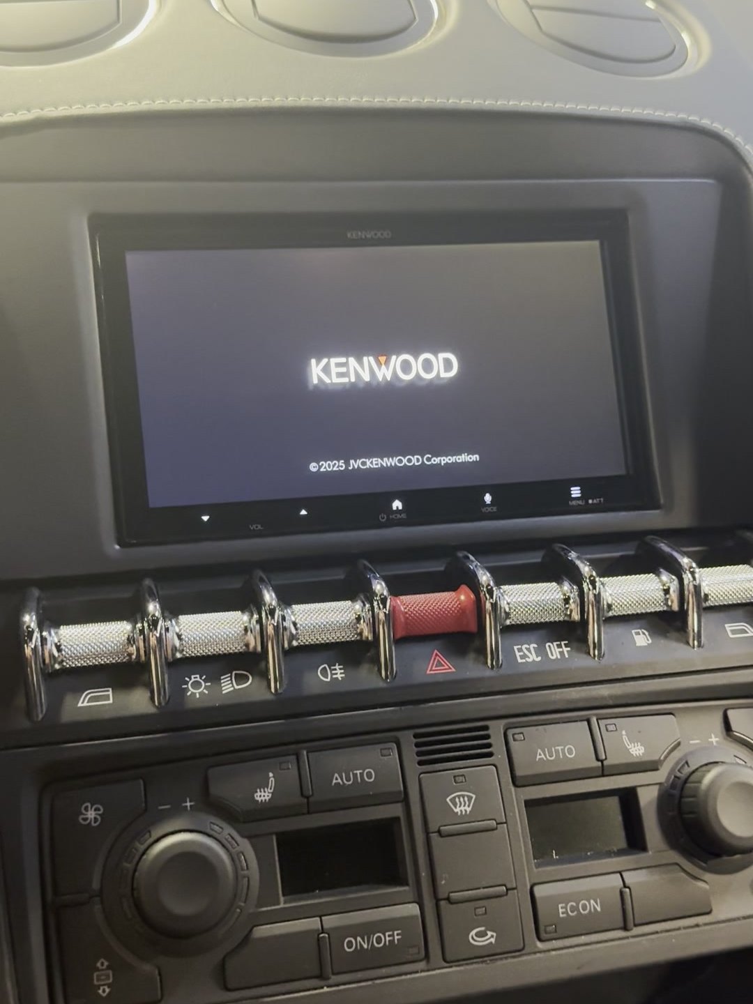 The Kenwood receiver starting up in the Gallardo dash, above the factory switch panel and climate controls