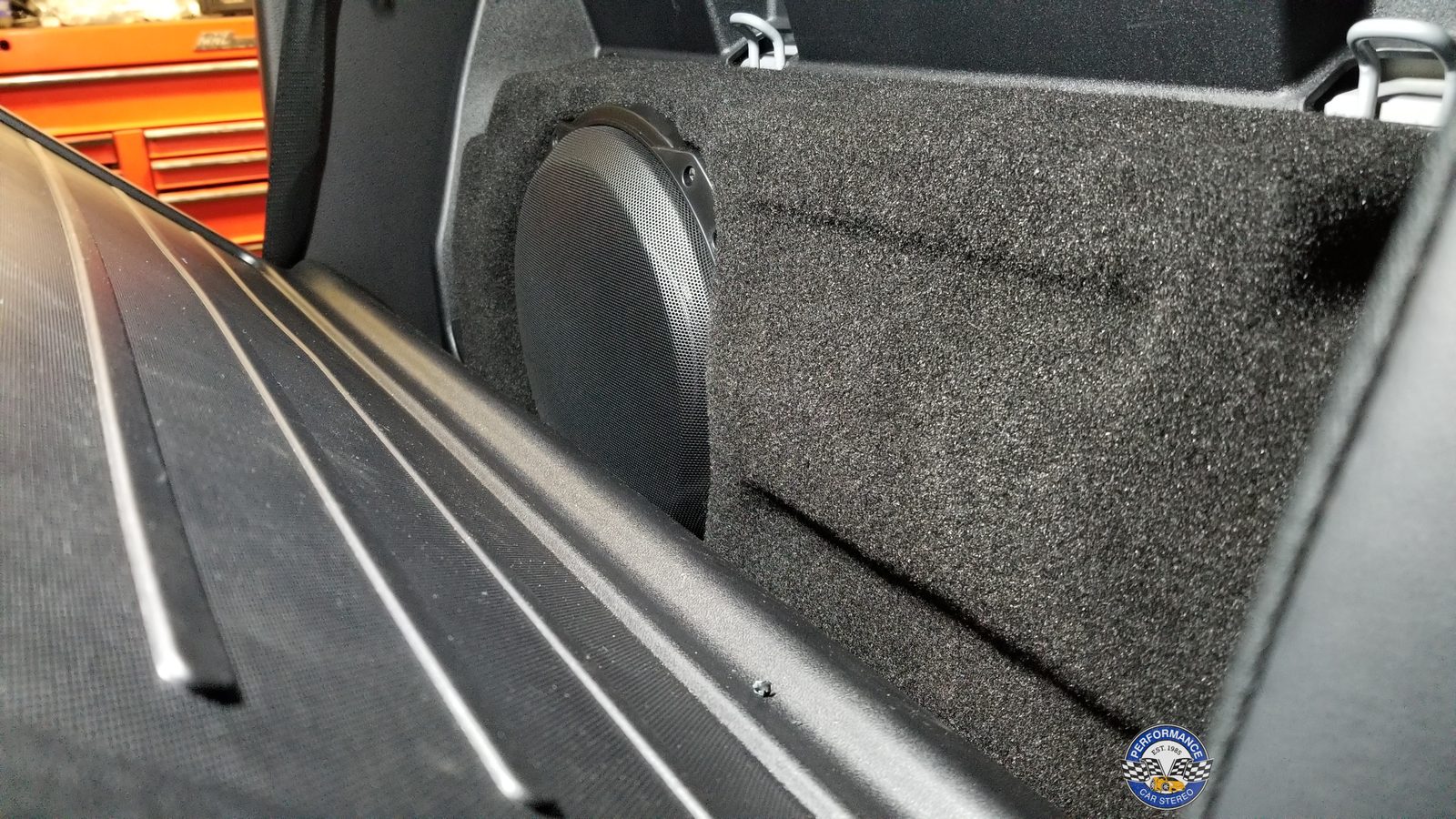 The Stealthbox installed behind the Tacoma's rear seat, its carpeted face matching the cab trim, with the seat folded to show it in place